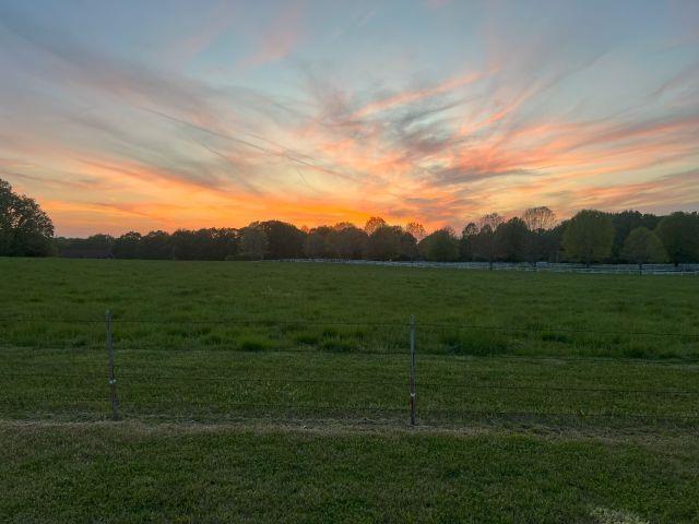 yard at dusk featuring fence and a rural view