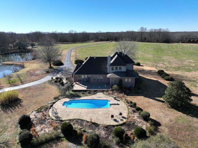 pool with a patio, a water view, and a rural view