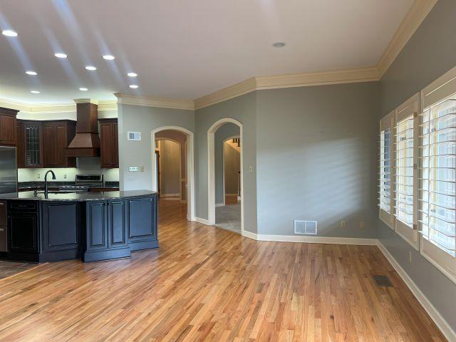 kitchen with visible vents, arched walkways, appliances with stainless steel finishes, premium range hood, and ornamental molding