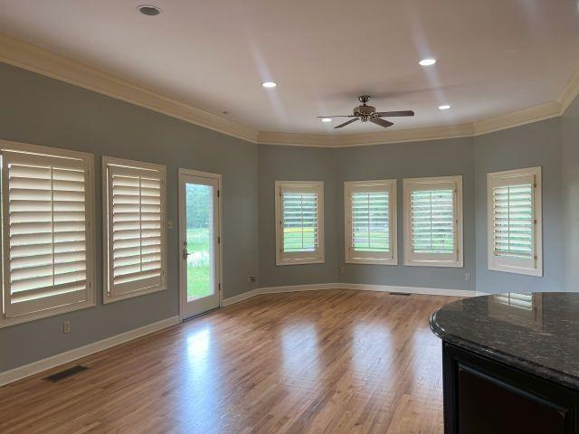 unfurnished living room featuring crown molding, ceiling fan, wood finished floors, and visible vents