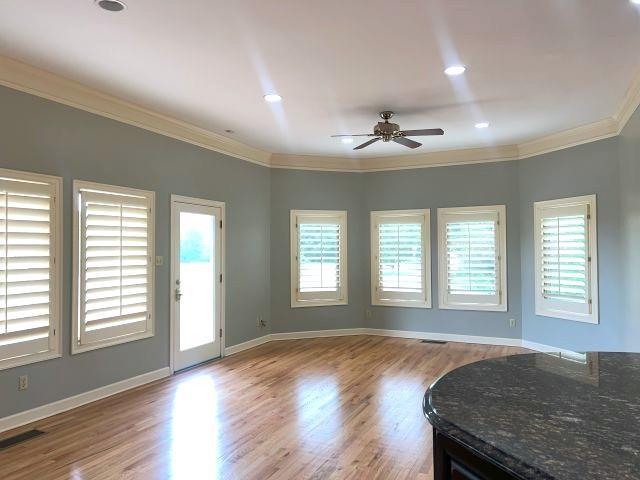 unfurnished living room with plenty of natural light, ornamental molding, a ceiling fan, and visible vents