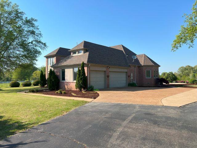 view of front of home with brick siding, an attached garage, driveway, and a front yard