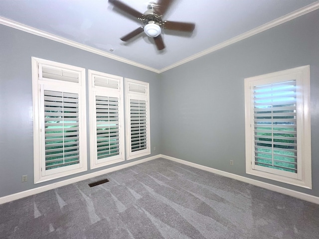 carpeted empty room with crown molding, baseboards, ceiling fan, and visible vents