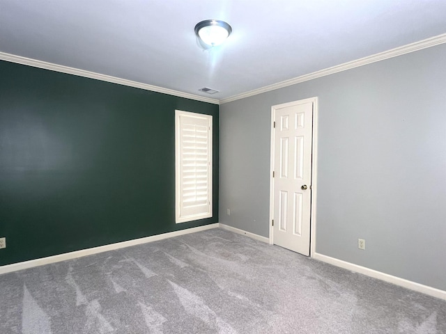 carpeted spare room featuring crown molding, baseboards, and visible vents