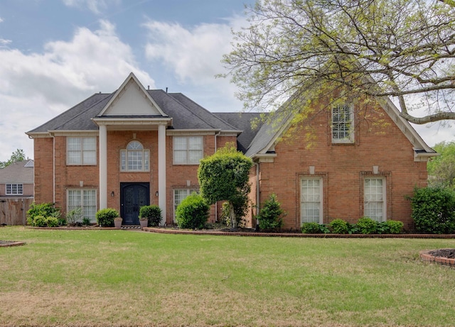 greek revival house featuring brick siding and a front lawn