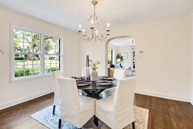 dining area featuring ornamental molding, a chandelier, arched walkways, baseboards, and dark wood-style flooring