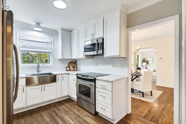 kitchen with decorative backsplash, appliances with stainless steel finishes, a sink, and white cabinets