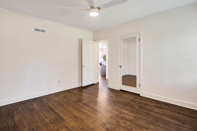 empty room featuring wood finished floors, visible vents, a ceiling fan, ornamental molding, and baseboards