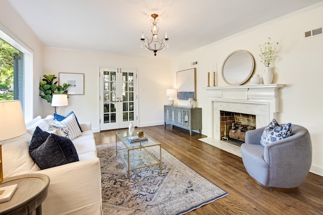 living room with baseboards, visible vents, a chandelier, wood finished floors, and a fireplace