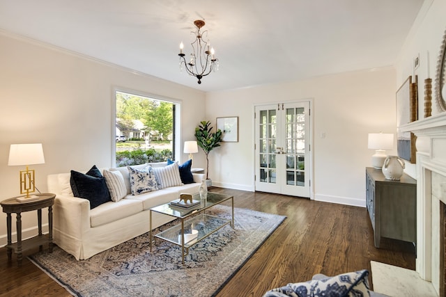living area featuring an inviting chandelier, a high end fireplace, wood finished floors, french doors, and baseboards