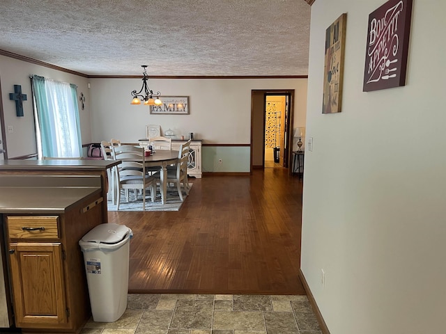 dining area with baseboards, a textured ceiling, a chandelier, and ornamental molding