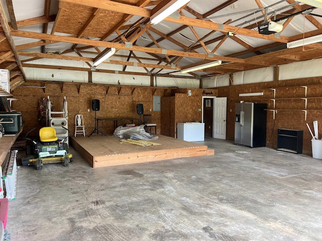 garage featuring refrigerator, stainless steel refrigerator with ice dispenser, a garage door opener, and electric panel