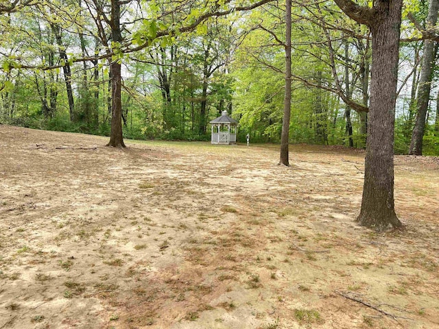view of yard with a gazebo and a wooded view