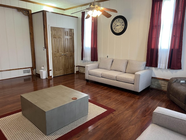 living area featuring a decorative wall, a ceiling fan, wood finished floors, and visible vents