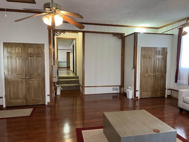 living room with wood finished floors, visible vents, a ceiling fan, ornamental molding, and a textured ceiling