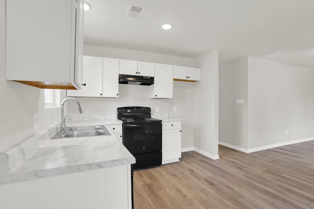 kitchen featuring light wood finished floors, under cabinet range hood, visible vents, black range with electric stovetop, and a sink