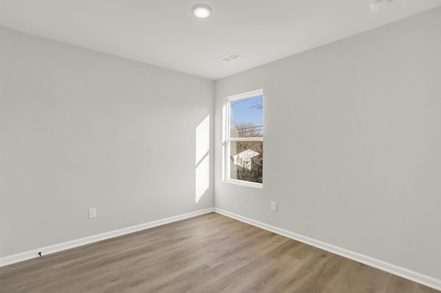 empty room with baseboards, wood finished floors, and visible vents