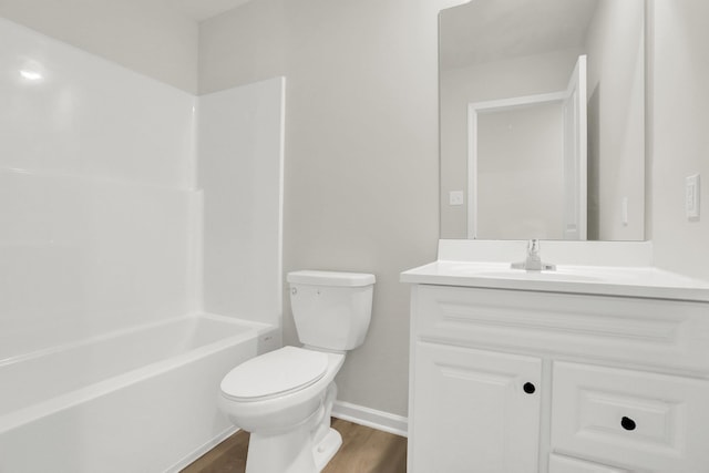 bathroom with toilet, baseboards, wood finished floors, vanity, and shower / tub combination