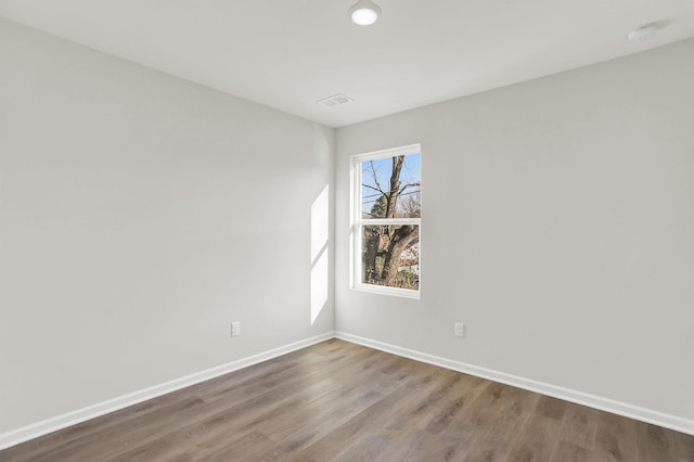 spare room with baseboards, wood finished floors, and visible vents