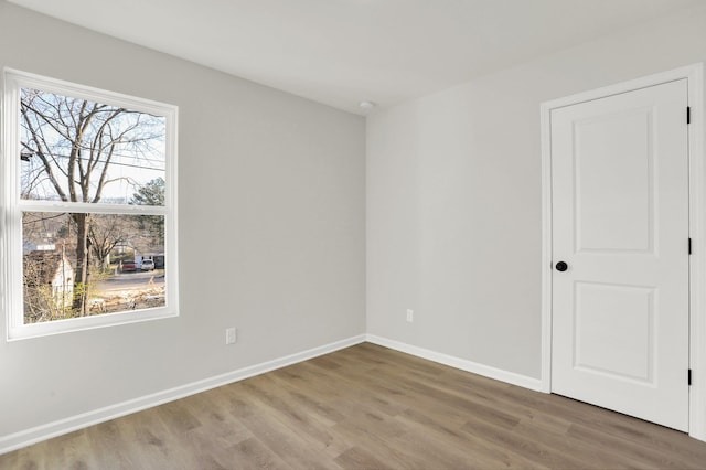 spare room featuring baseboards and wood finished floors