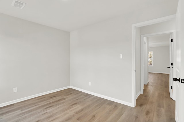 unfurnished room with visible vents, light wood finished floors, and baseboards