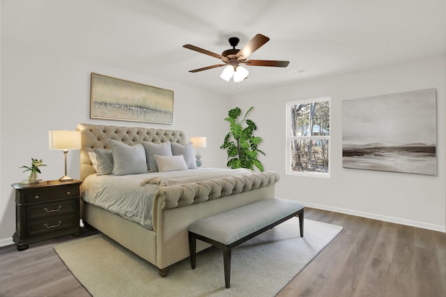 bedroom with wood finished floors, visible vents, a ceiling fan, and baseboards