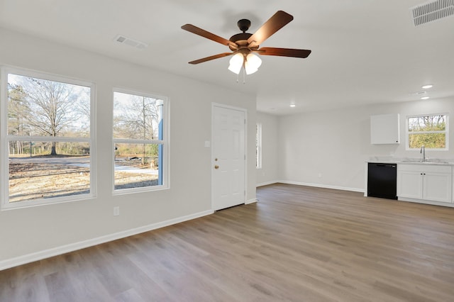 unfurnished living room featuring light wood-type flooring, visible vents, a sink, and recessed lighting