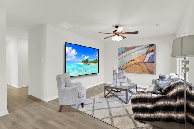 living room with wood finished floors, visible vents, baseboards, and ceiling fan