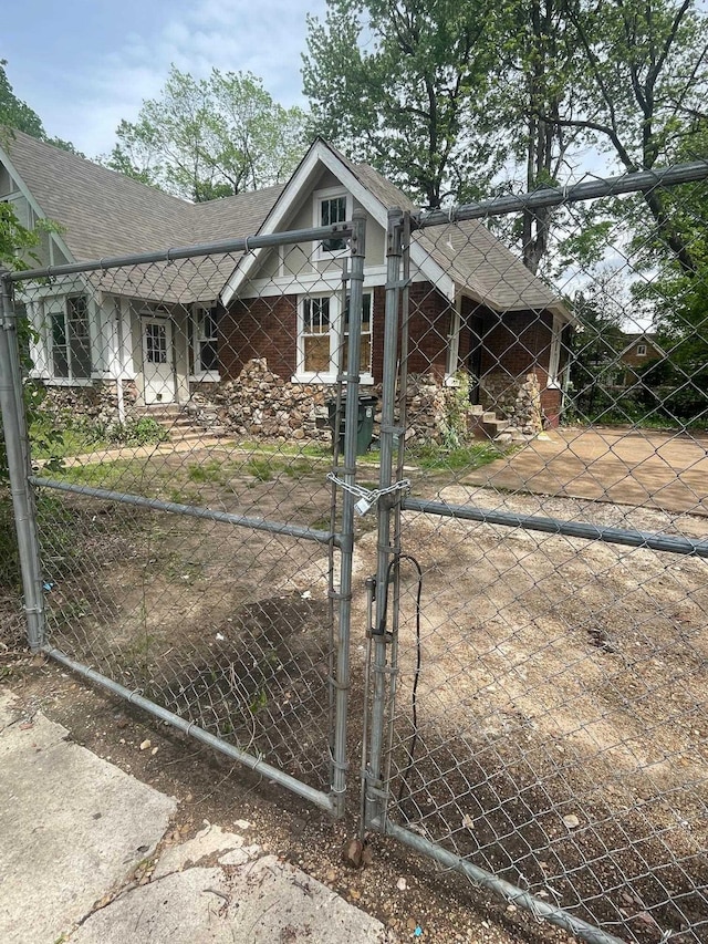 view of front of house with a gate, fence private yard, roof with shingles, and brick siding