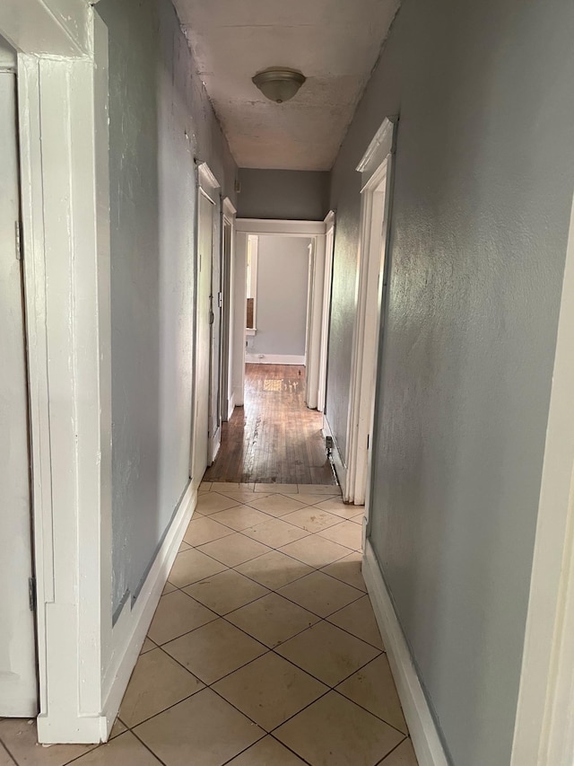 hall featuring baseboards and light tile patterned flooring