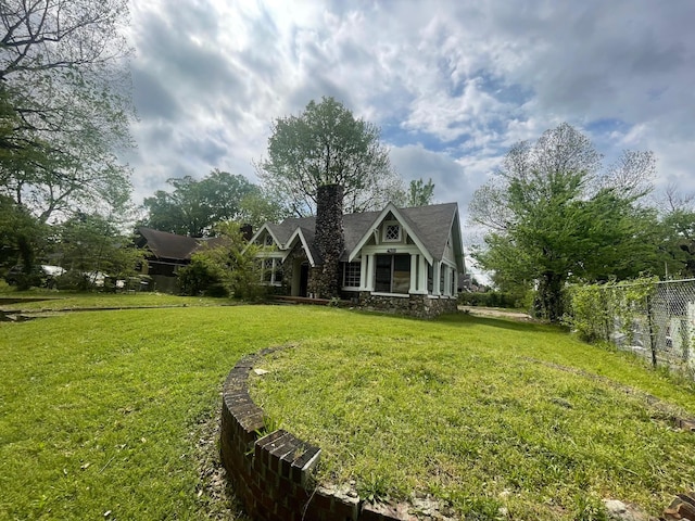 view of front facade with a chimney, a front lawn, and fence