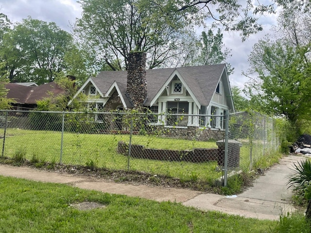 view of front of house with a chimney, a front yard, a shingled roof, and a fenced front yard