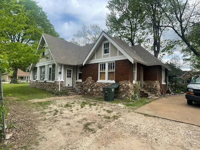 view of front facade featuring roof with shingles, brick siding, and concrete driveway