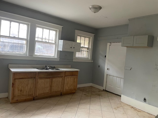 kitchen featuring light countertops, baseboards, a sink, and light tile patterned floors