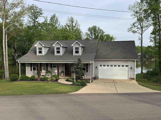 new england style home with an attached garage, a porch, a front yard, and concrete driveway
