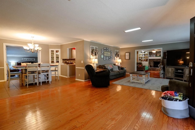 living area with hardwood / wood-style flooring, an inviting chandelier, ornamental molding, and a fireplace