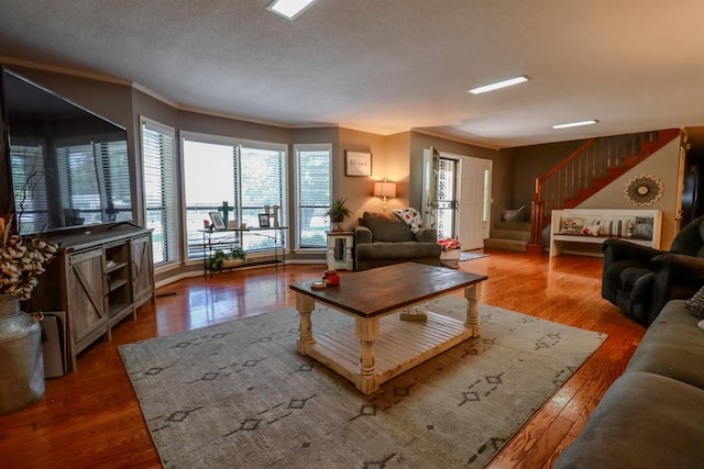 living area featuring wood finished floors, stairs, and ornamental molding