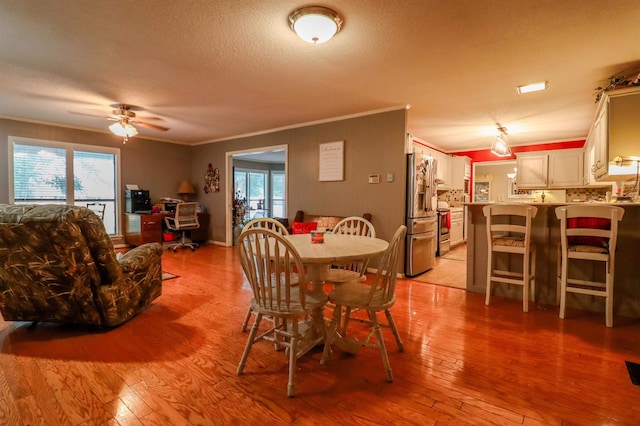 dining space with light wood finished floors, a healthy amount of sunlight, crown molding, and ceiling fan