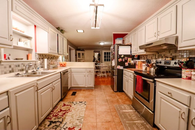 kitchen featuring under cabinet range hood, tasteful backsplash, a sink, and appliances with stainless steel finishes