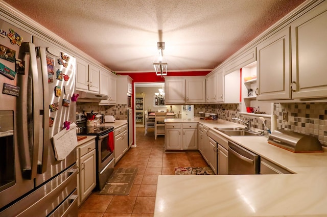 kitchen with tasteful backsplash, a sink, dark tile patterned flooring, appliances with stainless steel finishes, and under cabinet range hood