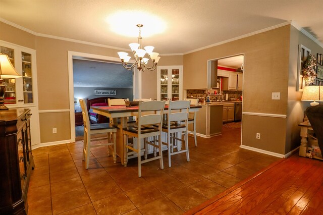 dining space with a chandelier, dark tile patterned floors, and ornamental molding