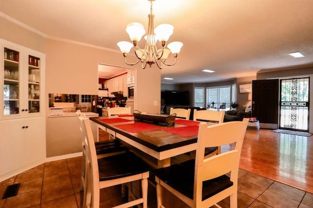 dining area with an inviting chandelier, crown molding, tile patterned floors, and visible vents