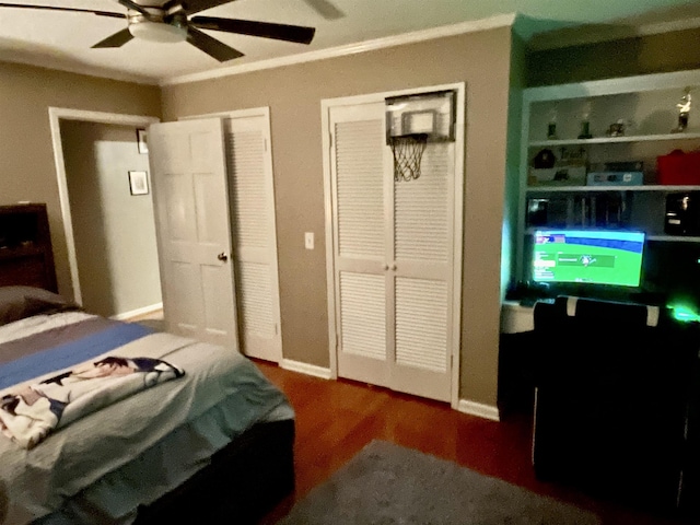 bedroom featuring two closets, crown molding, a ceiling fan, and wood finished floors