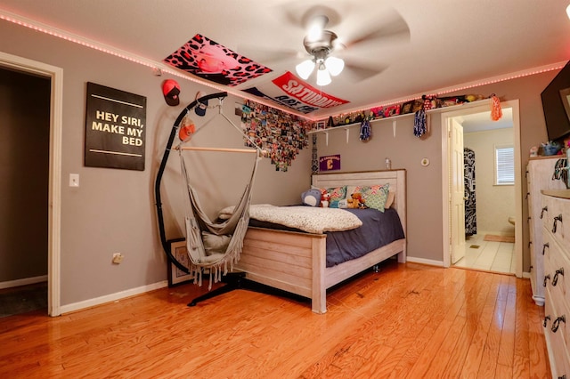 bedroom featuring light wood-type flooring, baseboards, ceiling fan, and connected bathroom