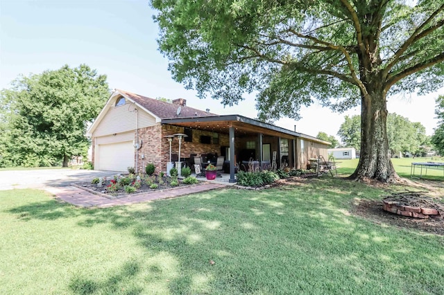 ranch-style home with a garage, driveway, brick siding, a front yard, and a trampoline