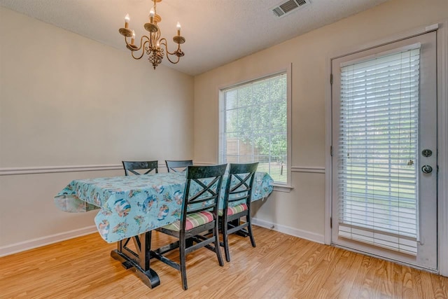 dining area featuring a chandelier, wood finished floors, visible vents, and baseboards