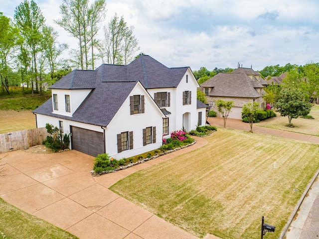 french country style house with a front lawn, concrete driveway, fence, a garage, and a shingled roof