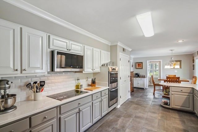 kitchen with tasteful backsplash, gray cabinetry, appliances with stainless steel finishes, light countertops, and ornamental molding
