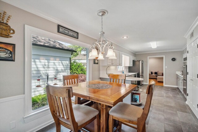 dining area with a chandelier, baseboards, and ornamental molding
