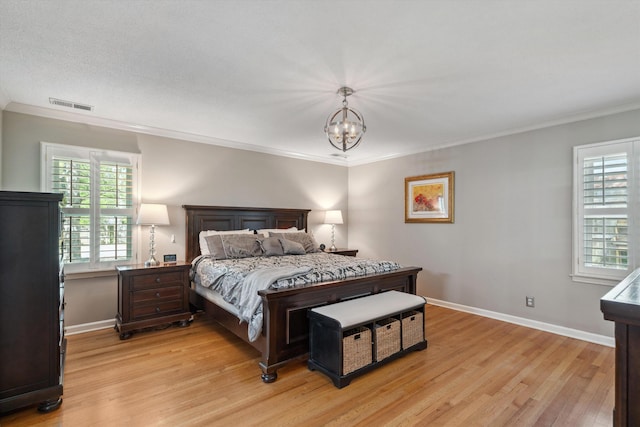 bedroom with ornamental molding, light wood finished floors, multiple windows, and visible vents